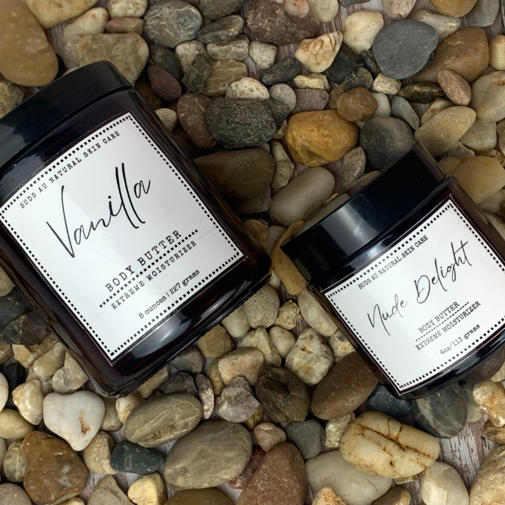 Vanilla and Nude Delight body butter in amber glass jar on top of rocks